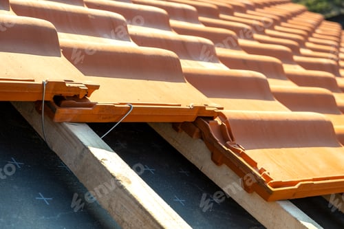 Preview: Closeup of metal montage anchor for installation of yellow ceramic roofing tiles