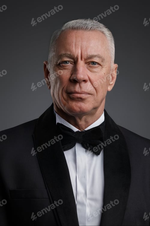 Preview: The old stylish man stands confidently in a black suit and bow tie