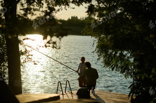 Preview: Father and son fishing together on wooden dock at sunset
