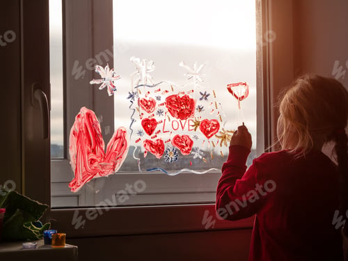 Preview: Little girl with paintbrush in hand drawing red heart Love on window glass. Valentine's day, dreams,