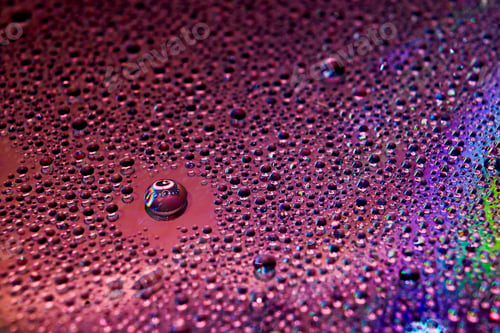 Preview: Selective focus shot of colorful reflective water drops on a digital disc surface