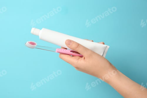 Preview: Woman holding toothbrush and paste against color background. Dental care