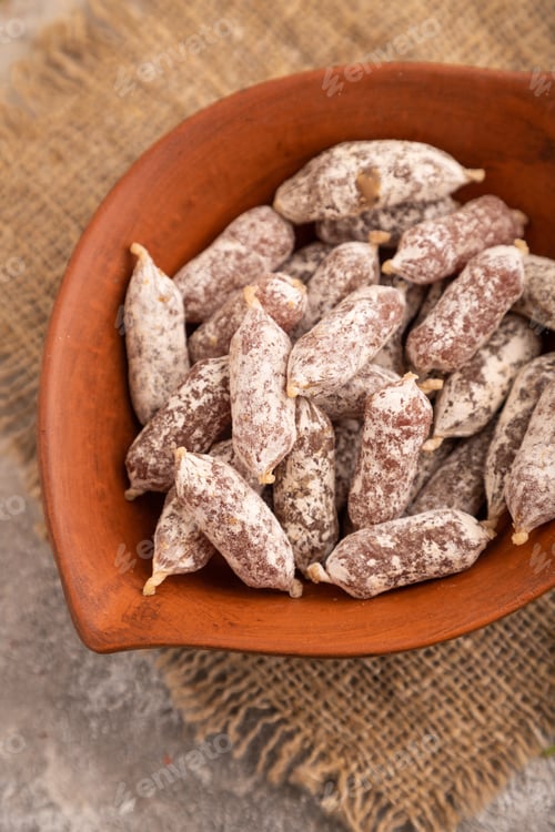 Preview: Small smoked Chicken sausages in clay bowl on brown concrete. side view, close up, selective focus