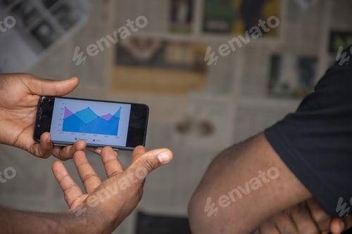 Preview: Closeup of two African people discussing a chart on a mobile device - future planning concept