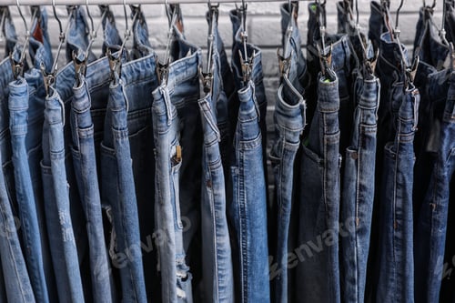 Preview: Rack with stylish jeans near brick wall, closeup