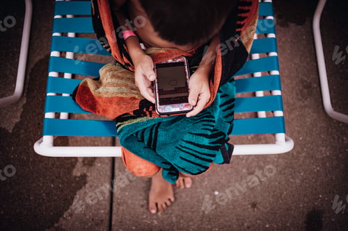 Preview: Boy playing on mobile device at the pool