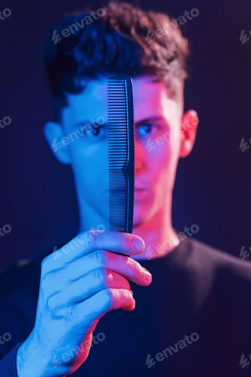Preview: Young barber with work equipment standing in the studio with neon lighting