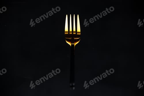Preview: Elegant shiny golden fork on black blurred background with free space in close up view