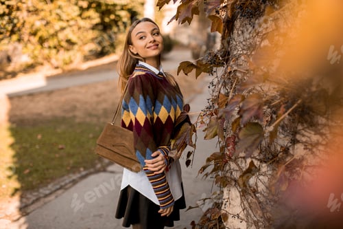 Preview: Young woman standing outside at sunny autumn day