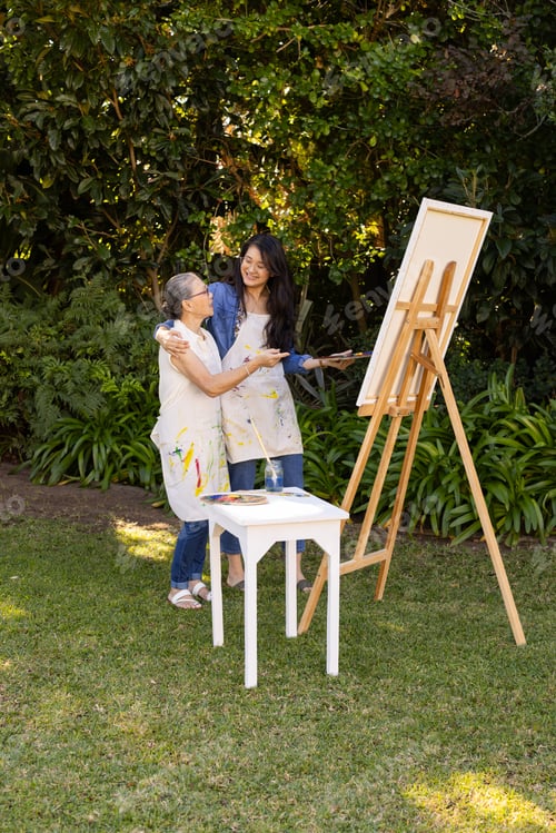 Preview: Painting on canvas, Asian granddaughter and grandmother enjoying outdoor art activity in garden