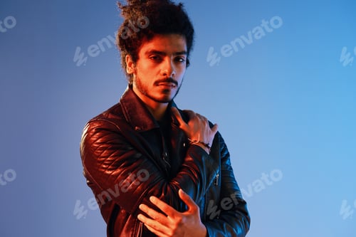 Preview: Portrait of a stylish man with curly hair on a blue background multinational, colored light, black
