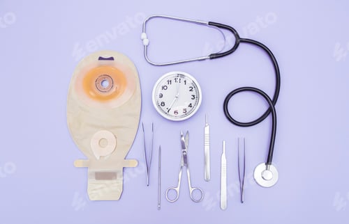 Preview: Colostomy bag, surgical instruments, stethoscope and clock with time seven lie on a light lilac.