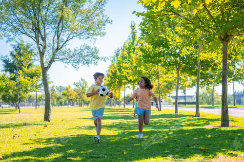 Preview: Children playing football and running in park