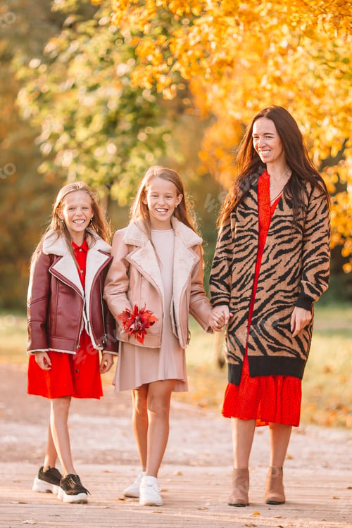 Preview: Little girl with mom outdoors in park at autumn day