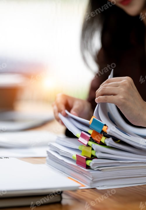 Preview: Businesswoman hands working in Stacks of paper files for searching and checking unfinished document