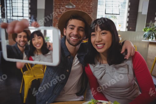 Preview: Happy man with woman taking selfie at cafe