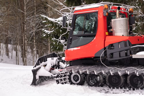 Preview: A snowplow on red tracks standing in winter in the forest near the barn
