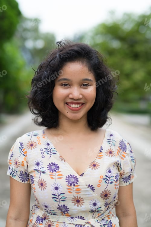 Preview: Beautiful Asian woman with short curly hair smiling outdoors