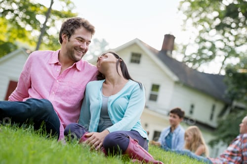 Preview: A couple sitting on the grass at a summer party.