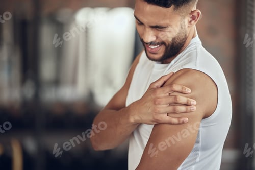 Preview: Young athlete experiencing arm pain. Bodybuilder with a bicep cramp in the gym. Fit young man with