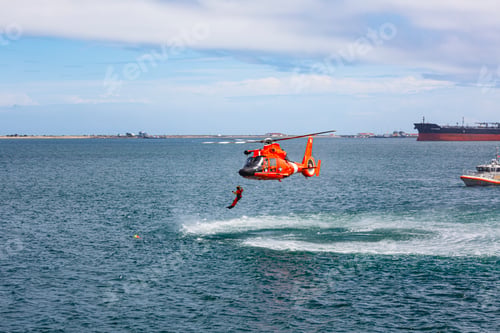 Preview: US Coast Guard helicopter hovering over the water in a demo of a rescue for a sea swimmer.