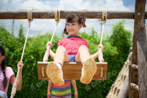Preview: Childrens having fun swinging on a swing on a clear day