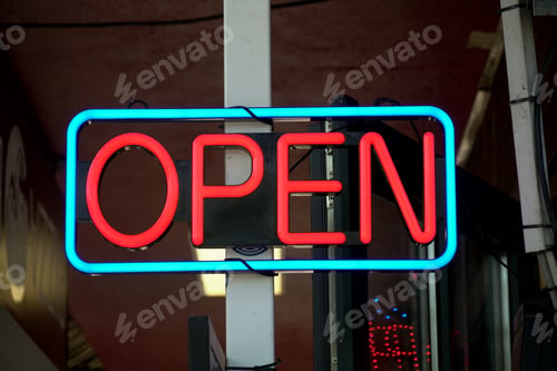 Preview: Closeup shot of an illuminated neon light sign with red open text on the steel post