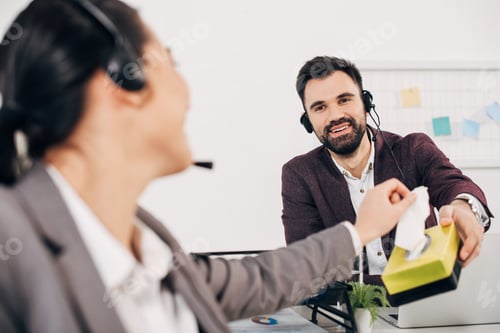 Preview: smiling call center operator giving napkins to coworker in office