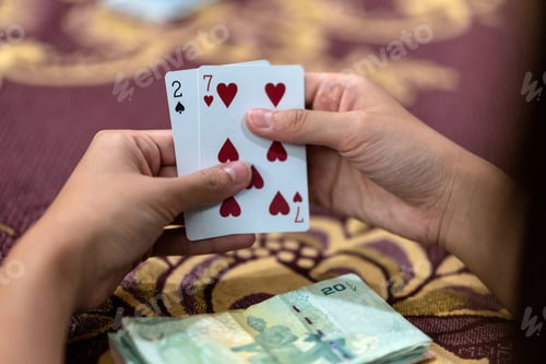 Preview: Reaw view closeup of asian woman playing card with money on the table over the carpet