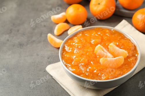 Preview: Tasty tangerine jam in bowl on grey table. Space for text