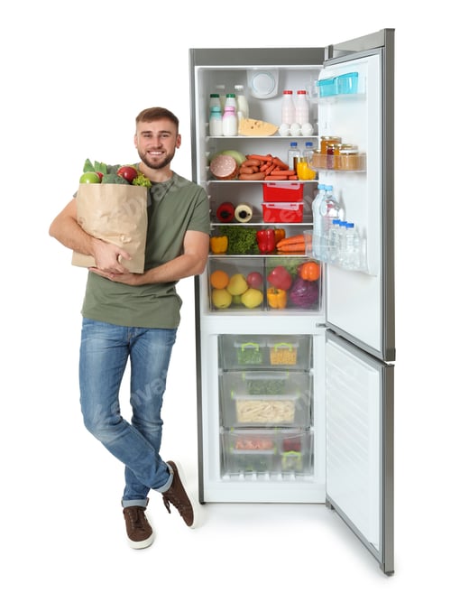 Preview: Young man with bag of groceries near open refrigerator on white background