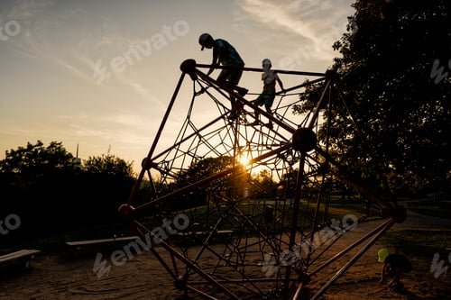 Preview: Silhouettes of children play in rope polyhedron climb at playground outdoor.
