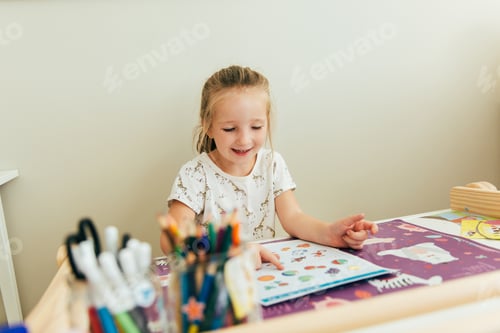Preview: Happy girl sitting at the table and studying. Homeschool. Kid doing homework