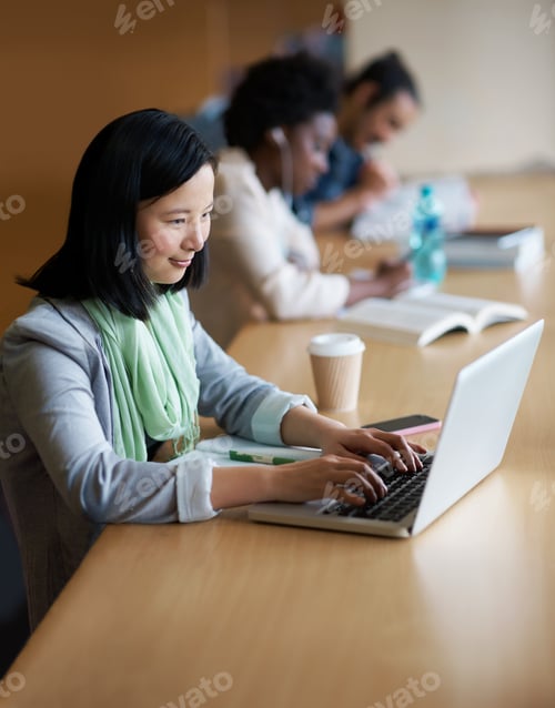 Preview: Working on her assignment. A young woman on a laptop in the library.