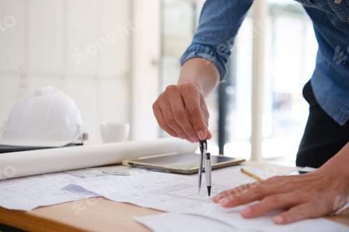 Preview: Architect designing house plans using a compass on a work desk in an office