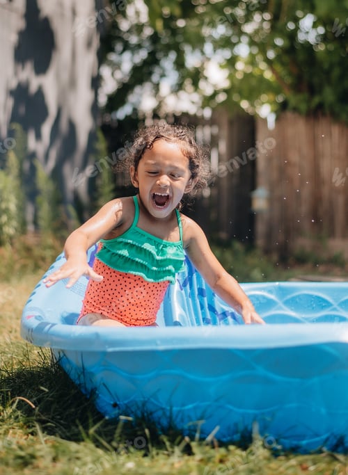 Preview: Happy girl outdoors in the summer having fun in kiddie pool