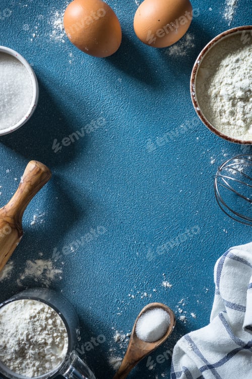Preview: Baking background ingredients. Flour, sugar, eggs and rolling pin at blue stone table.