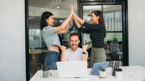 Preview: A team of happy, successful businesspeople sharing high-fives as they laugh.