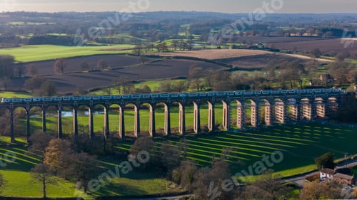 Preview: Train crossing a historic viaduct in a lush landscape