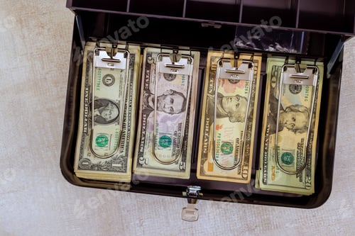 Preview: Open cash box filled with organized with American dollars banknotes arranged by denomination