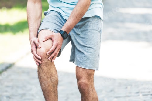 Preview: partial view of sportsman in fitness tracker touching injured knee