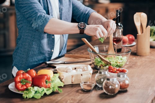 Preview: cropped shot of man preparing vegetable salad at home
