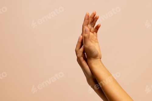 Preview: Crossed arms and touching hands of woman on pink beige background with copy space