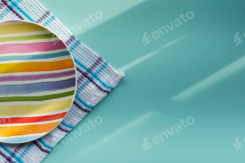 Preview: empty plate on a blue background, covered with the rays of the morning sun