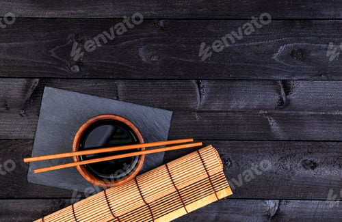 Preview: Background for sushi. Bamboo mat and soy sauce on black wooden table. Top view with copy space