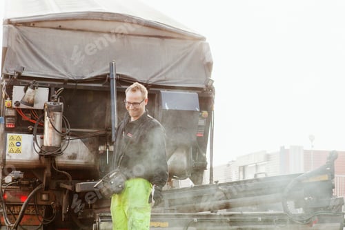 Preview: Worker standing proudly by a truck on a construction site