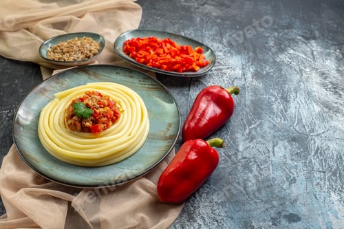 Preview: Front view of a blue plate with tasty pasta meal served with tomato and meat on tan color towel
