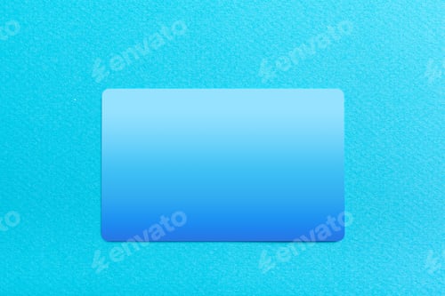 Preview: Bright blue card rests on smooth blue surface in soft light during daytime