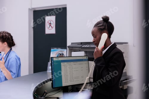 Preview: Receptionist talking at landline phone with remote patient discussing medical appointment detalies