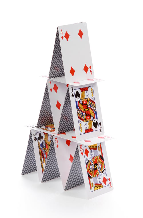 Preview: Closeup of a three-story card house isolated on a white background